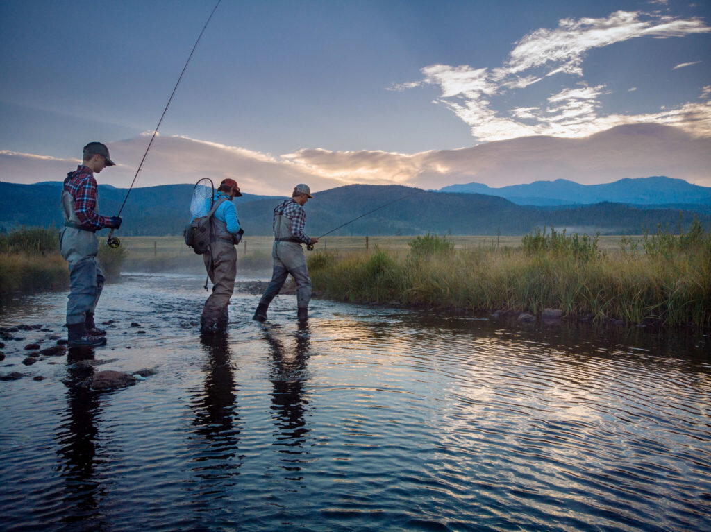 Men wading in river water while fishing