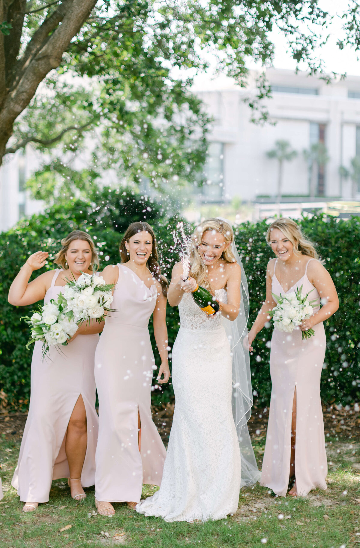 A bride pops champagne with her bridesmaids.