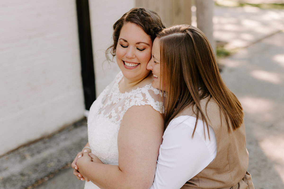 Two brides embracing on wedding day