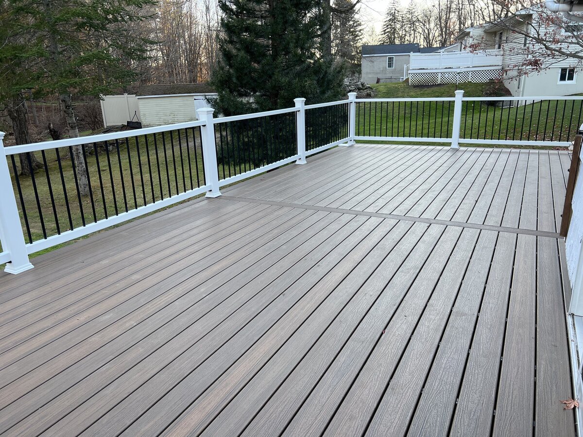 Worcester Deck Builder Work On A Composite brown deck with white and black PVC railings on a white house