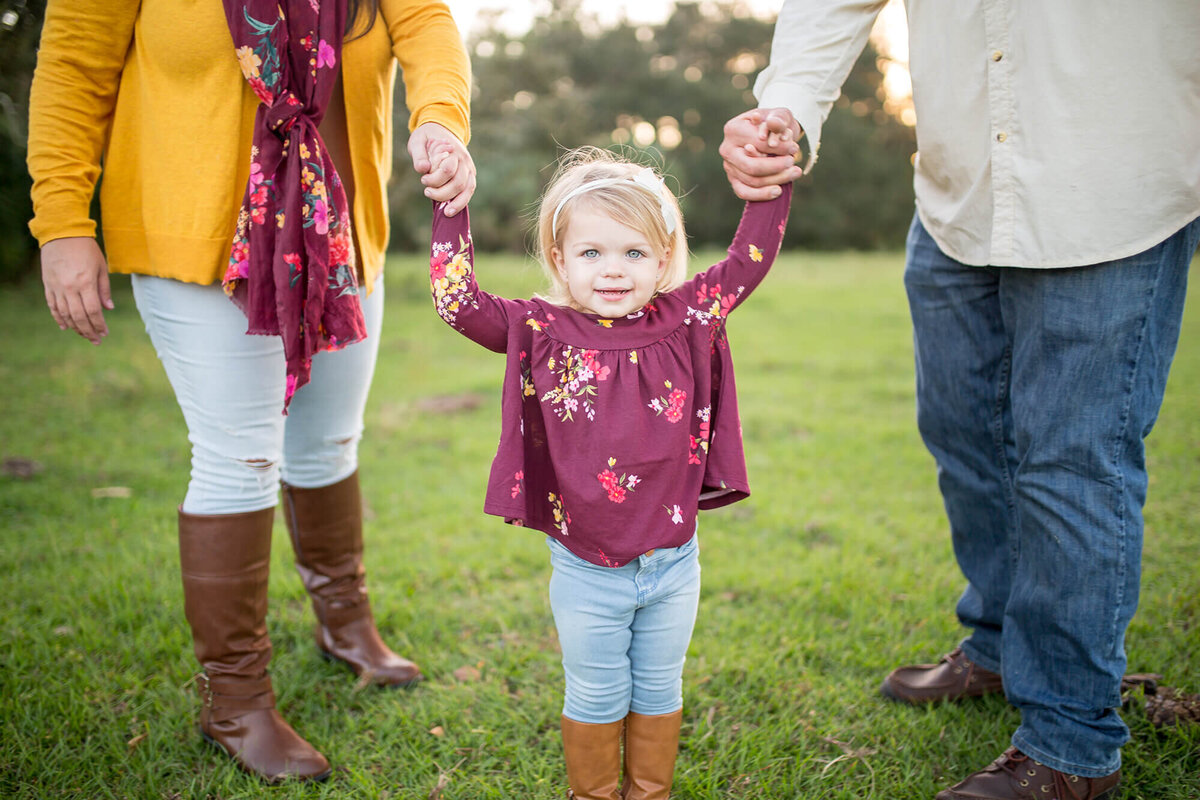 Farm family session with closeup of little girl holding parents hands. Located on private property in Bradenton, FL 