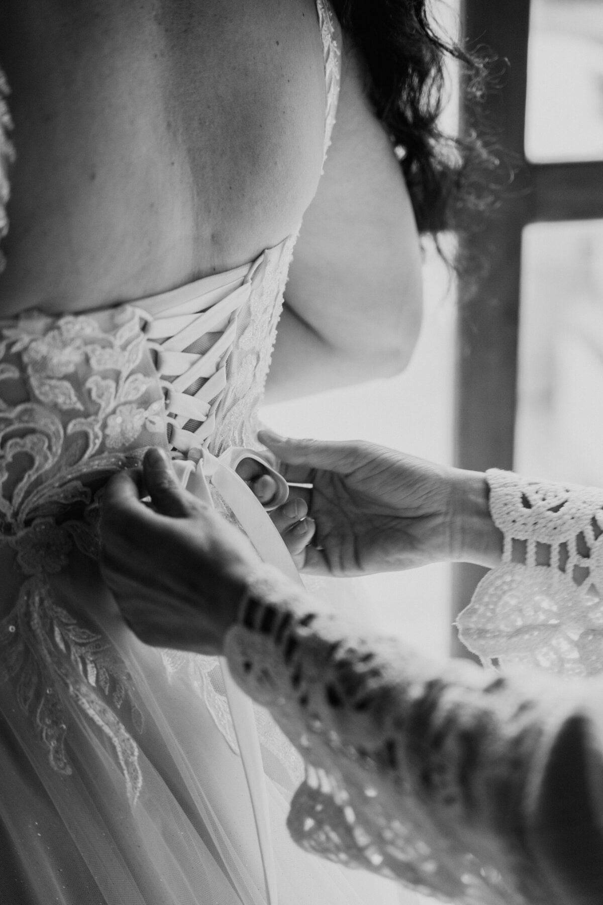 Hands tightening lace-up back of wedding gown