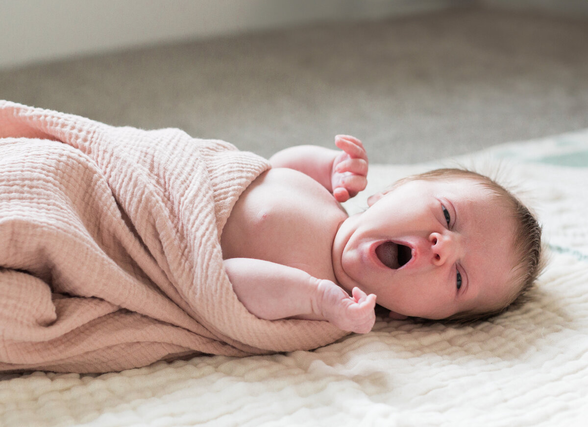 Side profile of newborn baby yawning during an in-home session in Denver