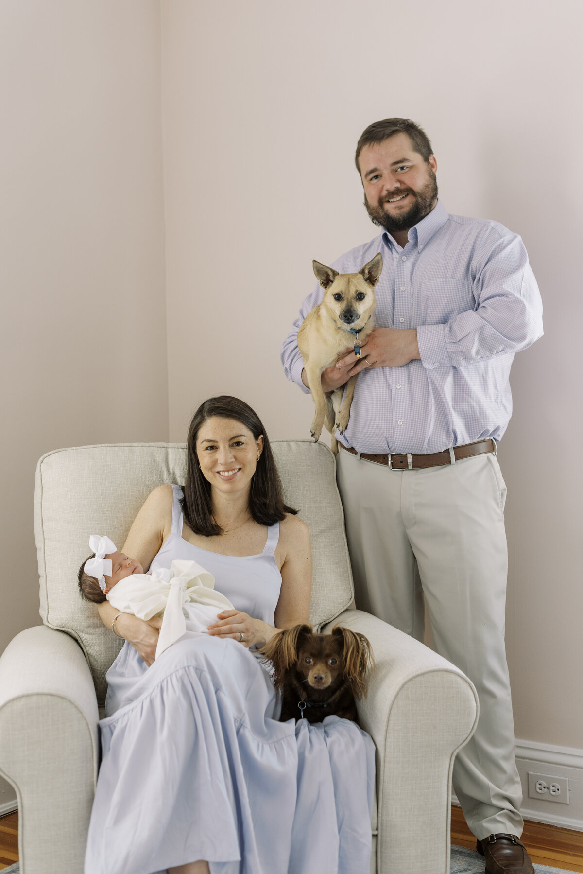 parents holding newborn with dogs