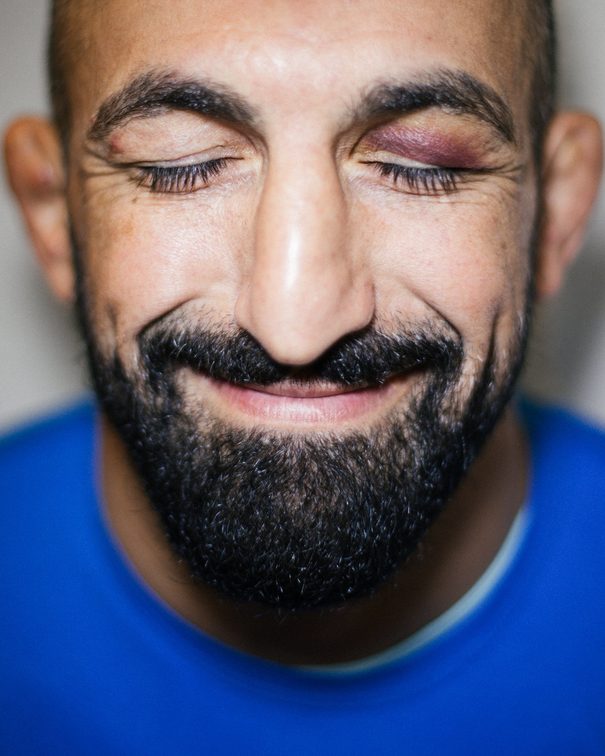 Reza Madadi, en av Sveriges mest kända fighters inom sporten Mixed Martial Arts (MMA), poserar på bild med sin blåtira. Fotot togs under en reportagefotografering för Fighter Magazine.