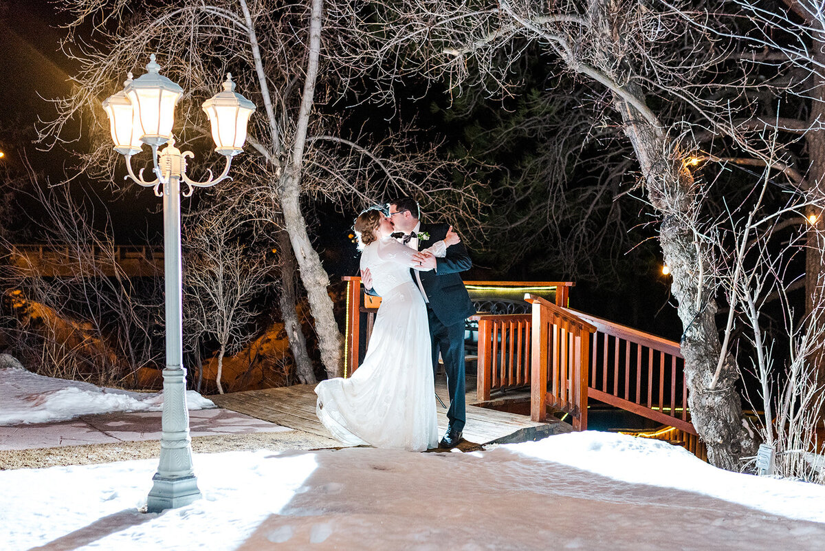 wedding couple kisses in the snow at night right before their final exit