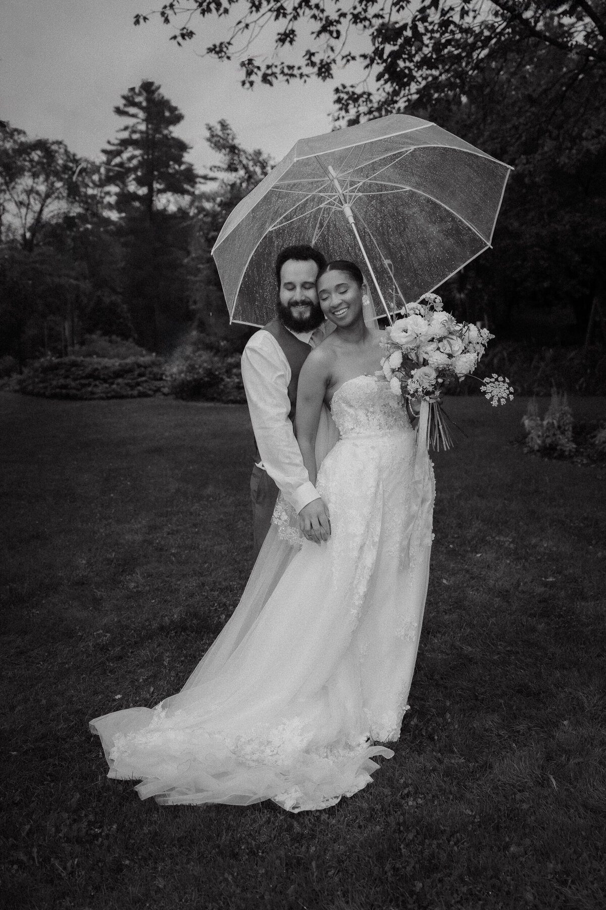 Couple de mariés sous un parapluie transparent lors d’un mariage pluvieux et moody dans les Laurentides, photographié par Jeff Gagnon photographe.