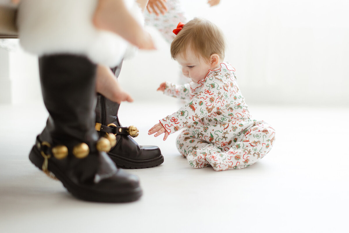Photo of a little baby playing with santas shoe bells for a branding/headshot session for Dondolo.