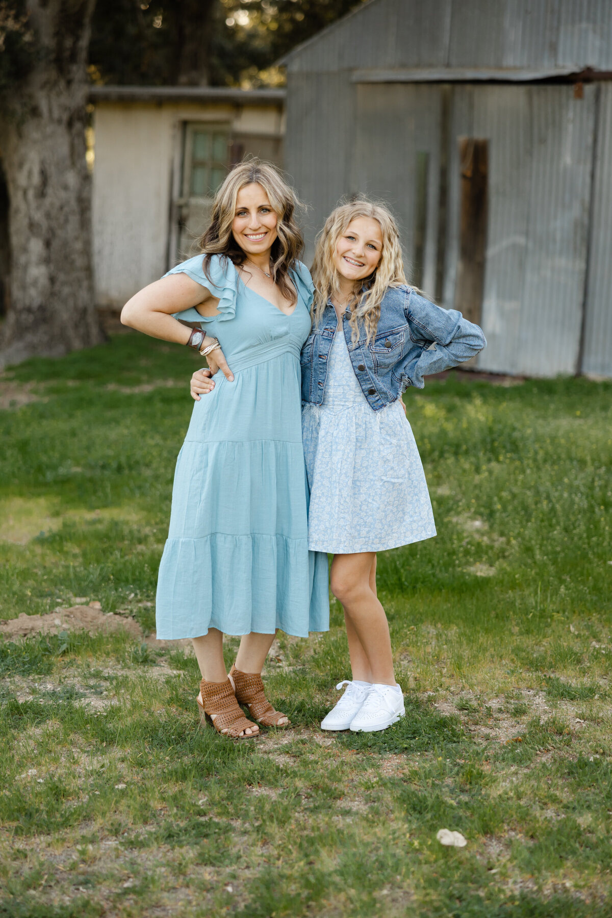 Mother and daughter smiling together outdoors in matching light blue dresses. Photographed by Yucaipa family photographer Kaitlyn Dawn Photography.