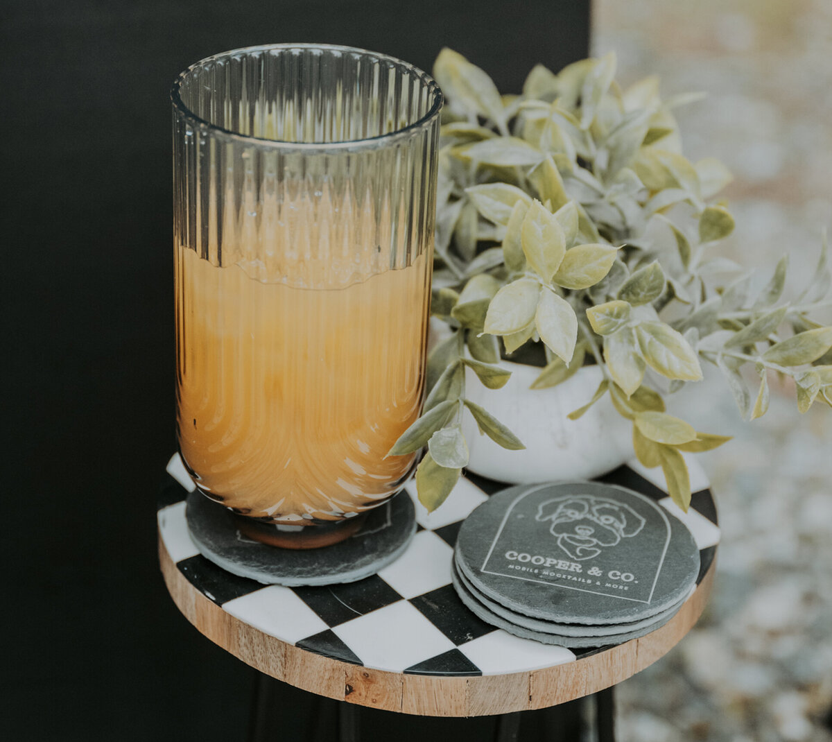 Mocktail on a checkerboard table with Cooper & Co branded coasters