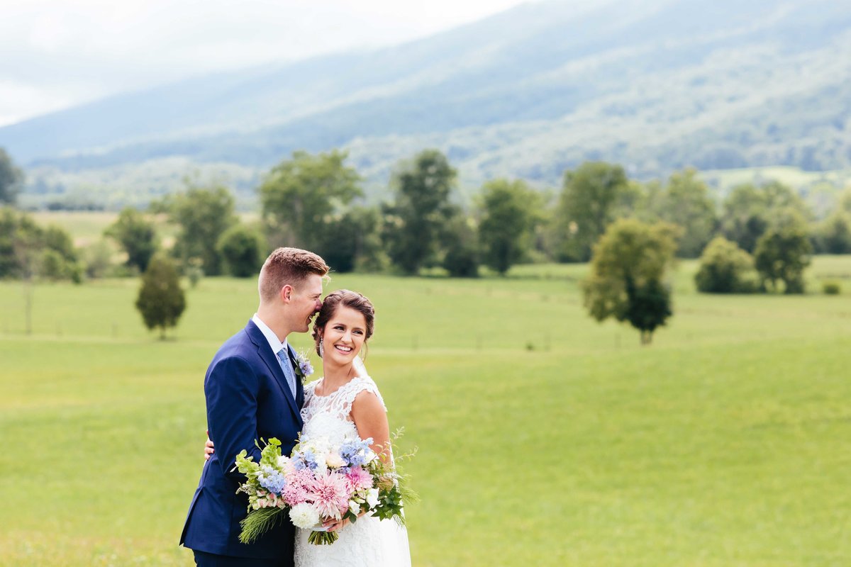 Husband kissing wife on temple at Crooked River wedding venue