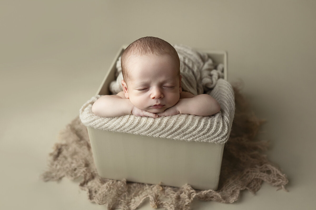 Baby boy posed in a cream colored box.