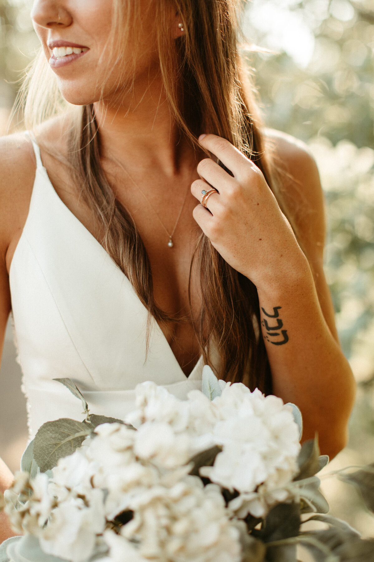 Natural bride wearing simple pearl necklace and holding faux floral bouquet
