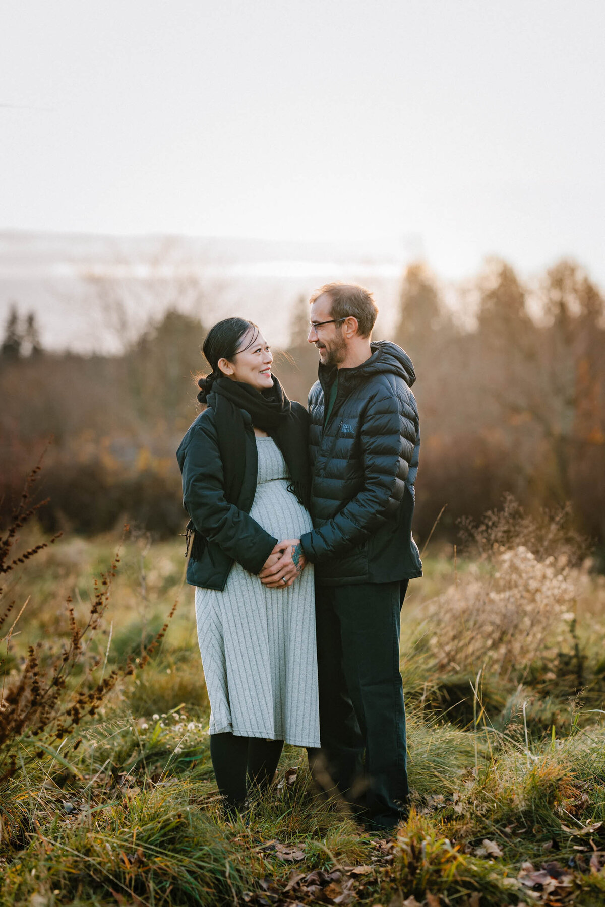 Pregnant couple lovingly touching the mother's belly, sharing a quiet, tender moment during their maternity session.
