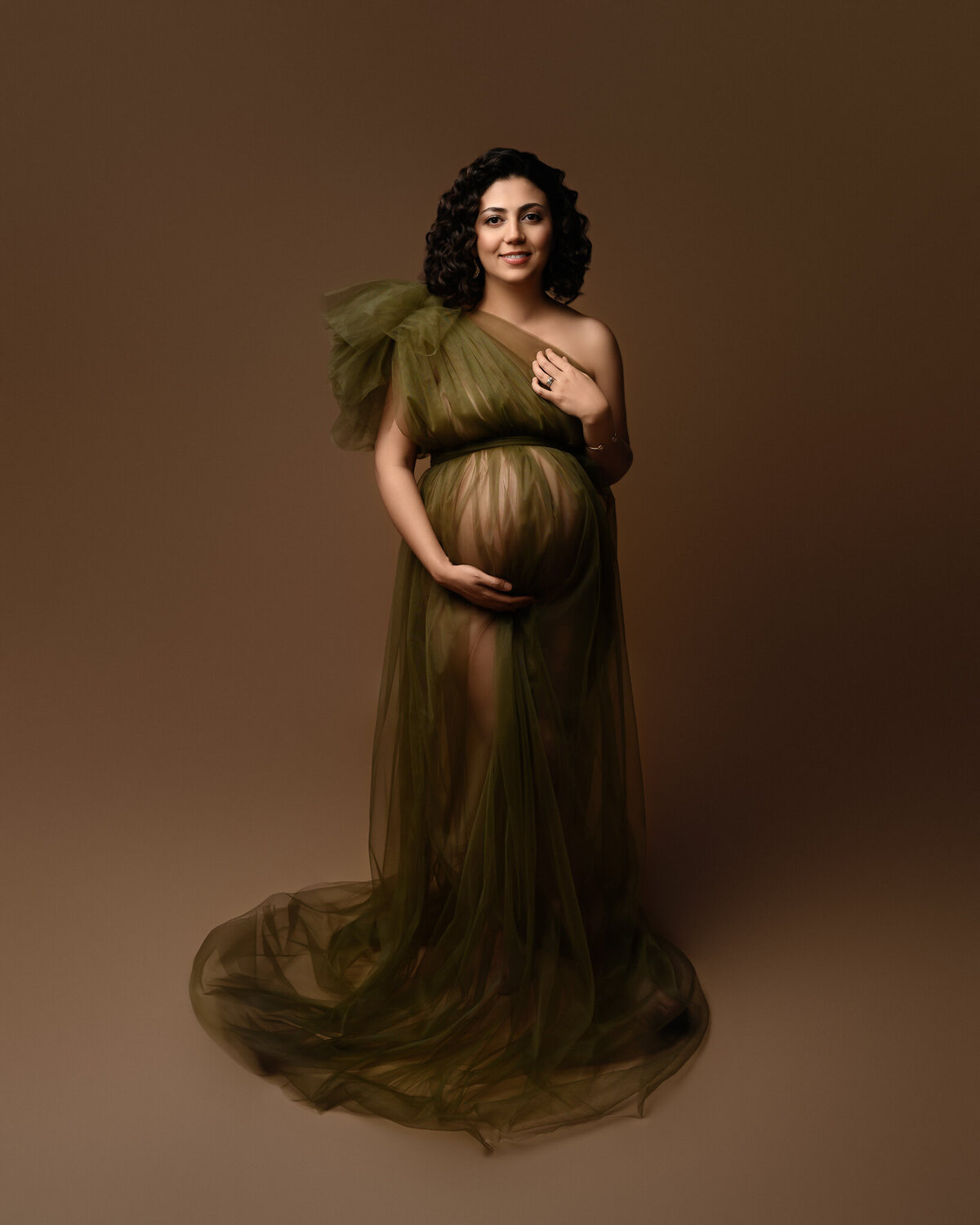 Studio maternity photo of a pregnant woman in a sheer olive green tulle gown, captured in Georgetown by a fine art photographer.