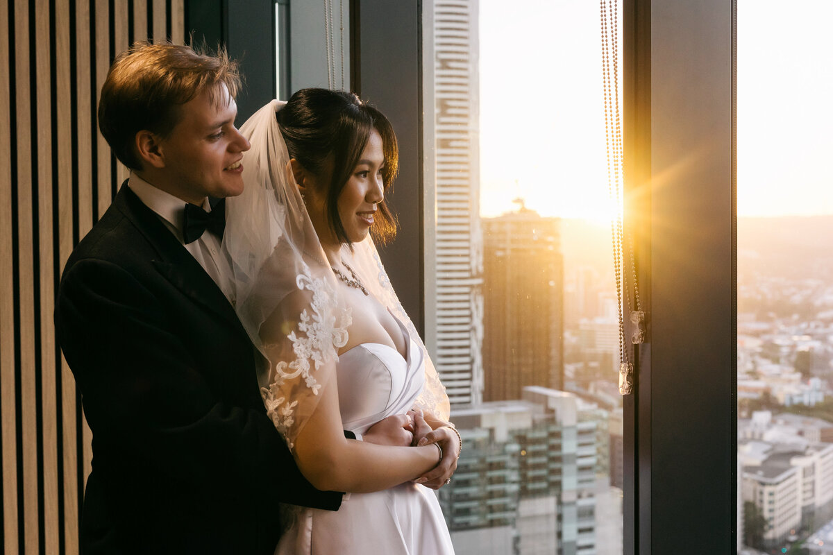 Close-up of a Brisbane Registry Office couple smiling and embracing in warm evening light inside the venue.