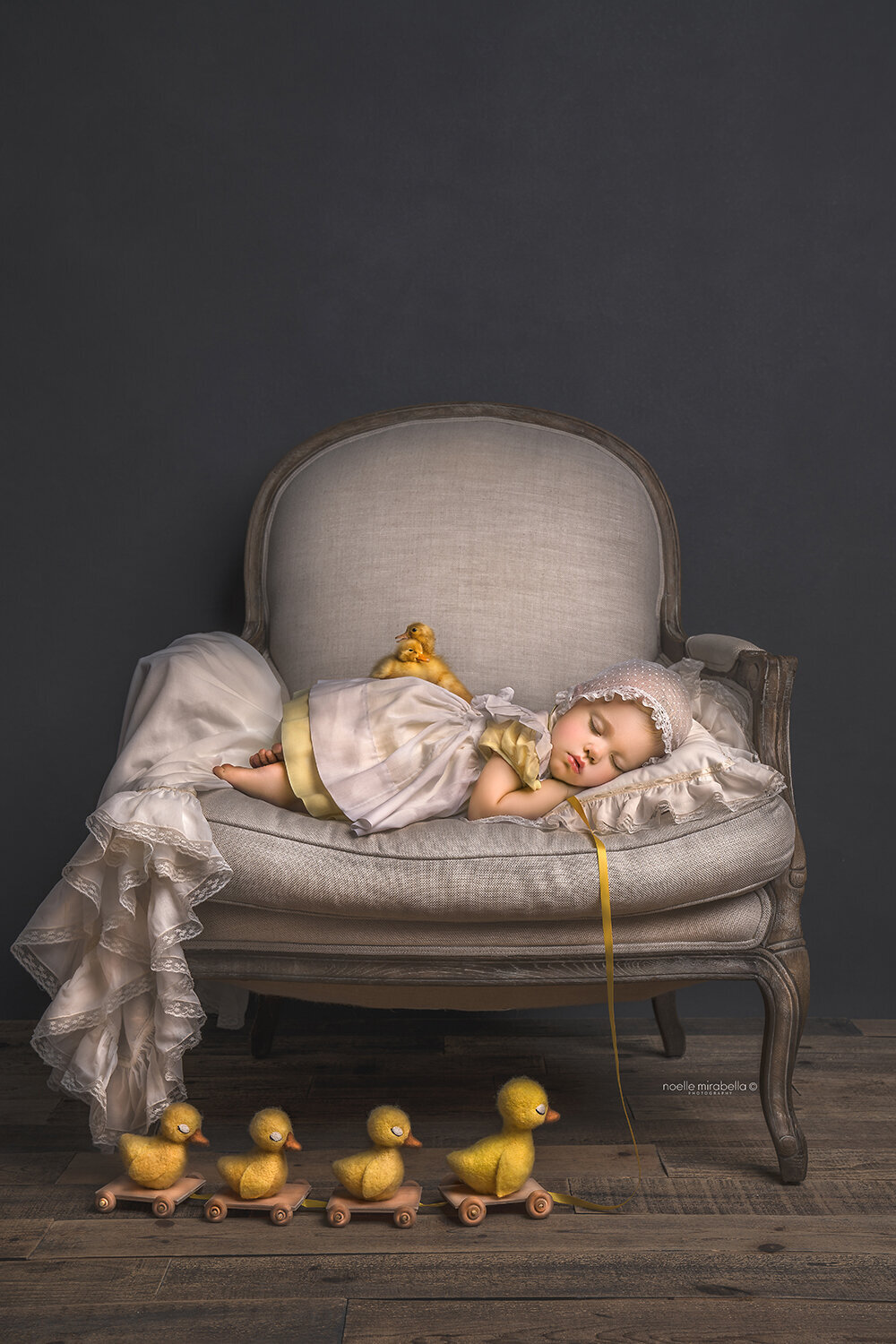 Girl in a Vintage dress sleeping with baby ducklings in a vintage french chair. Vintage style children's portrait. Duckling pull toy.