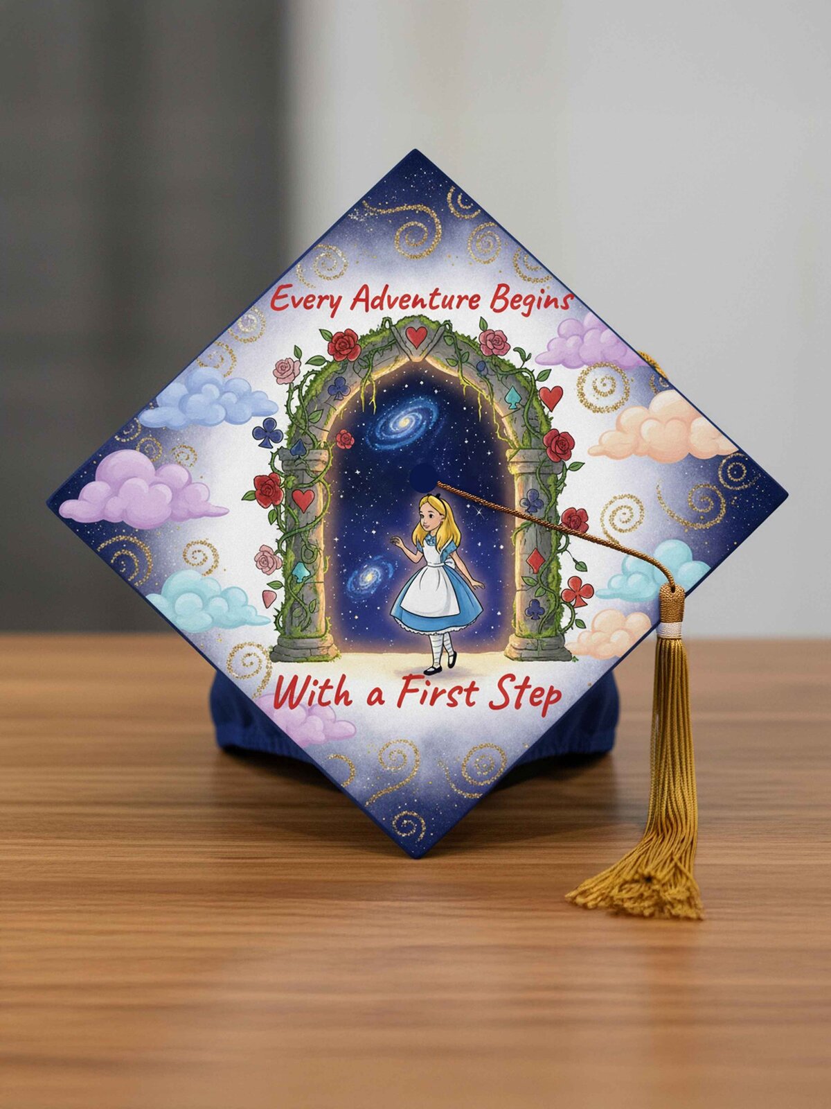 A branded photography shot of custom painted graduation cap with Alice in Wonderland theme and the quote "Every Adventure Begins With a First Step" quote 
