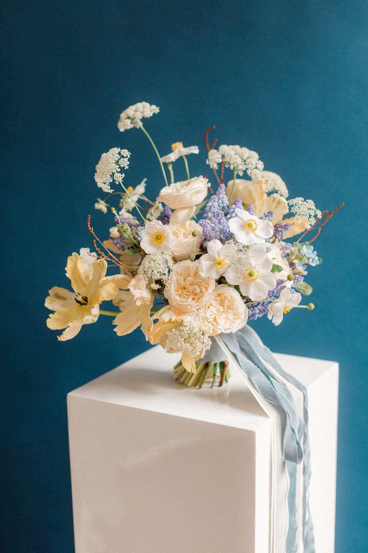 An airy bouquet of peach and lilac flowers in front of a blue backdrop at a Montreal studio.
