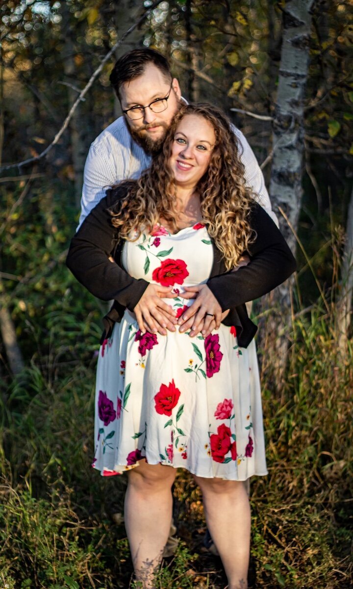 Pregnant mom with her husband and toddler daughter in a field in Edmonton
