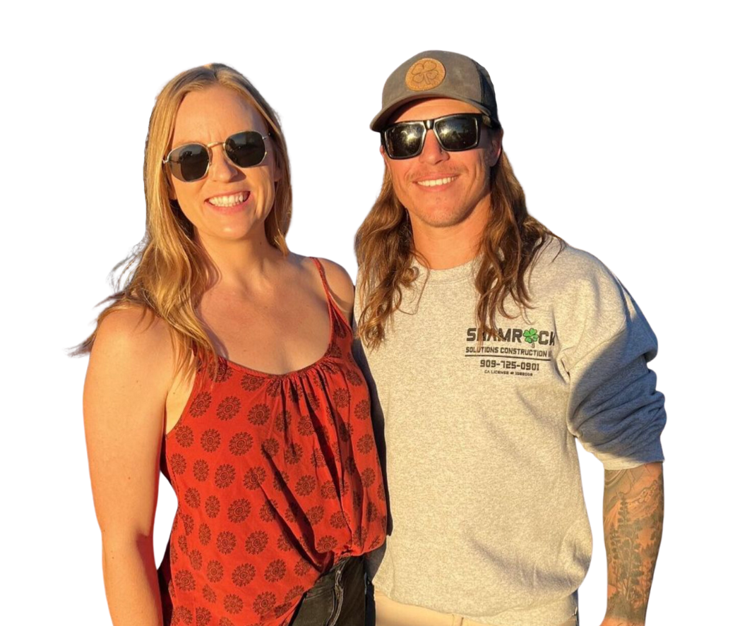 A blonde woman wearing sunglasses and a man with long dirty blonde hair, sunglasses, and a baseball cap smiling together.