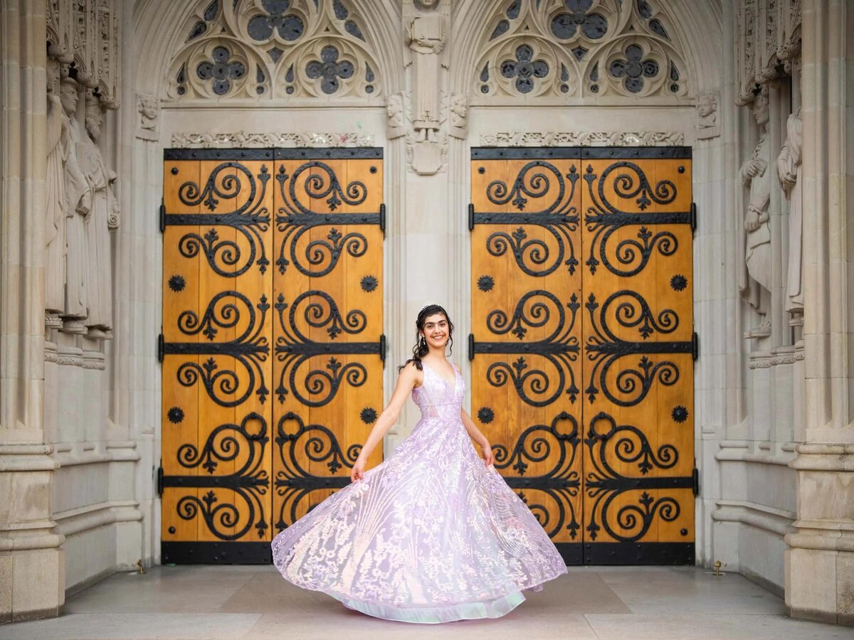 A girl standing in front of grand doors spinning her dress.