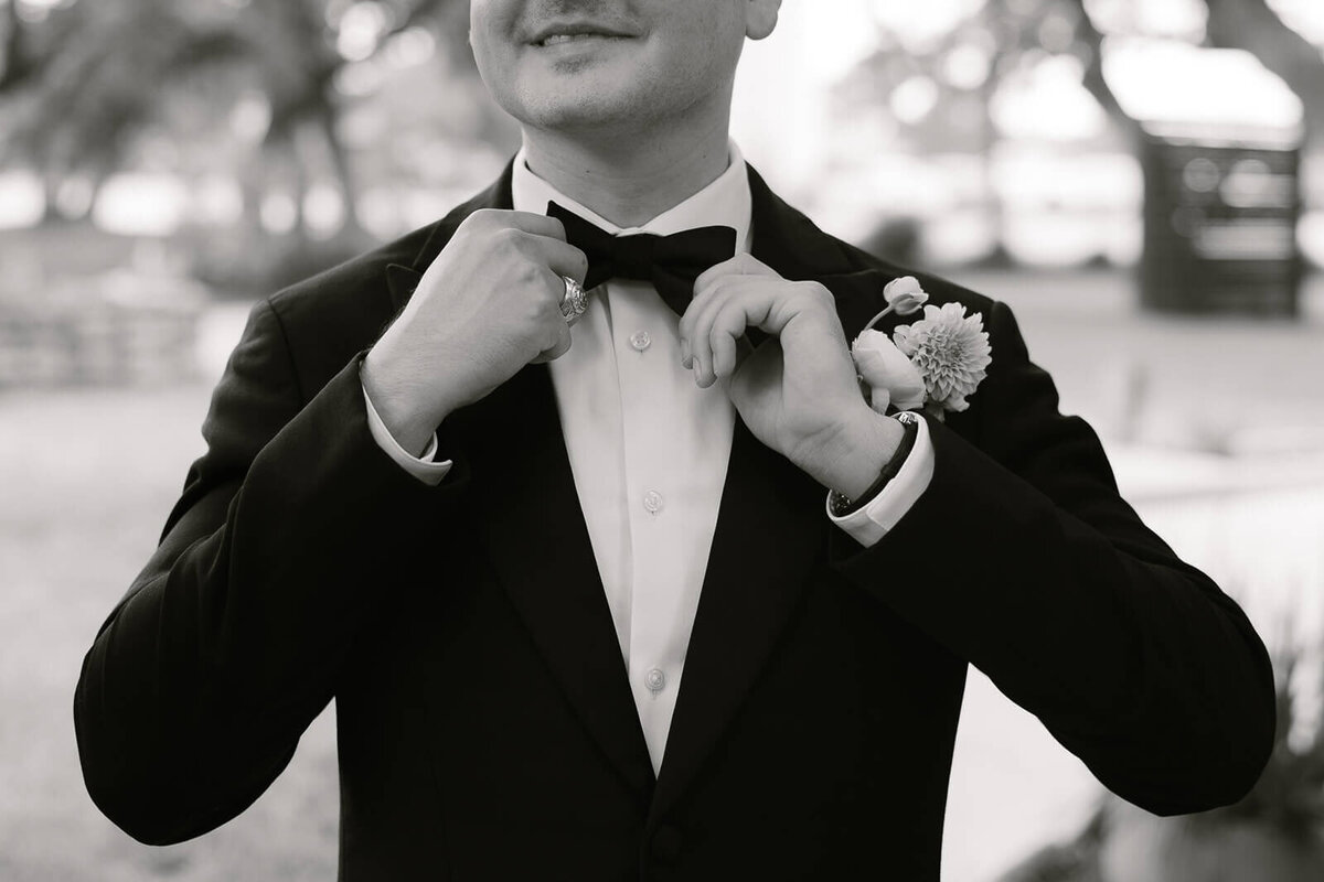 detail photo of the groom adjusting his bowtie