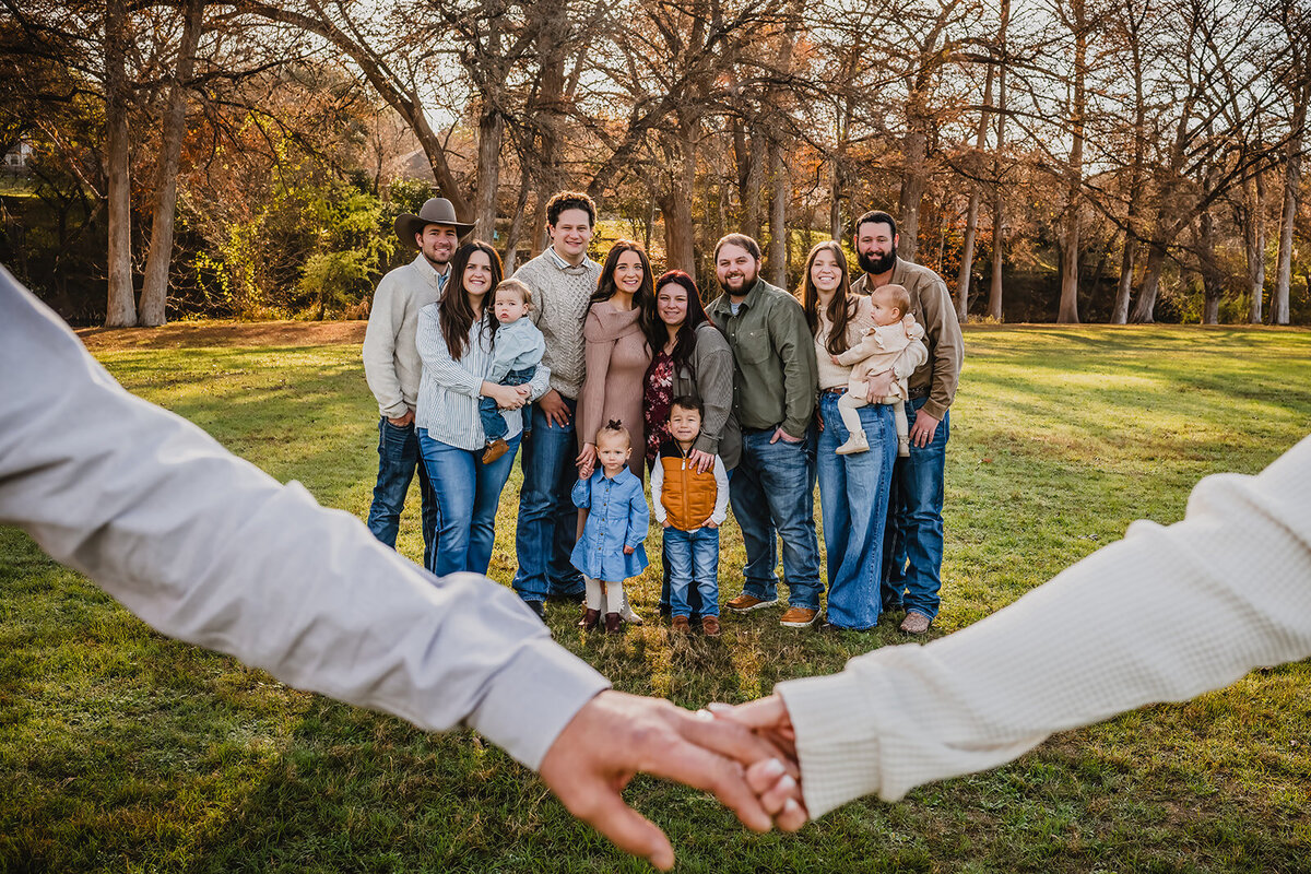 Large family session at Cypress Bend in New Braunfels, Texas. Full group shot with grandparents in front linking arms.