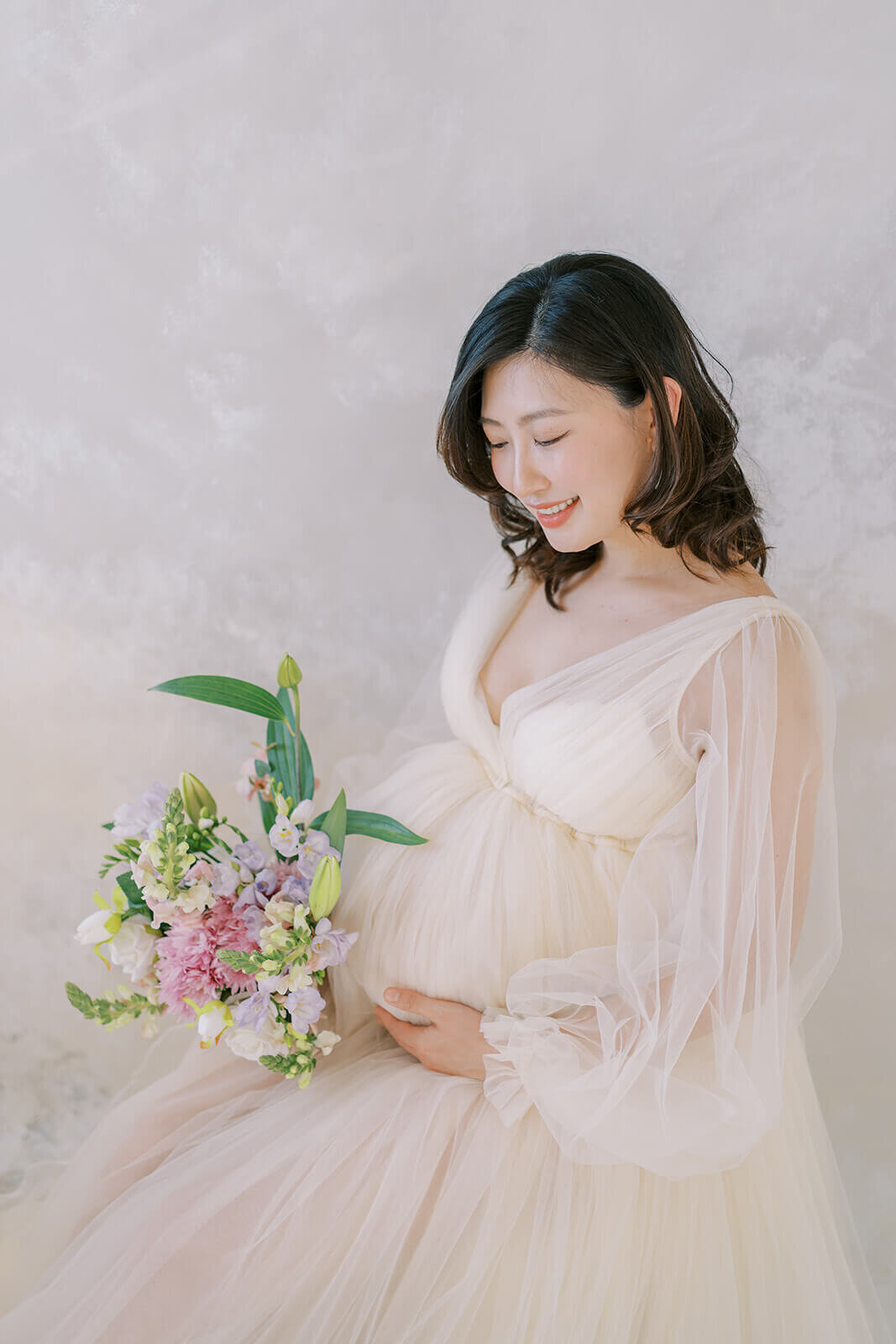 Cherish the glow of an expectant Chinese descent mum in a stunning cream tulle gown, capturing maternity magic at a Gold Coast studio