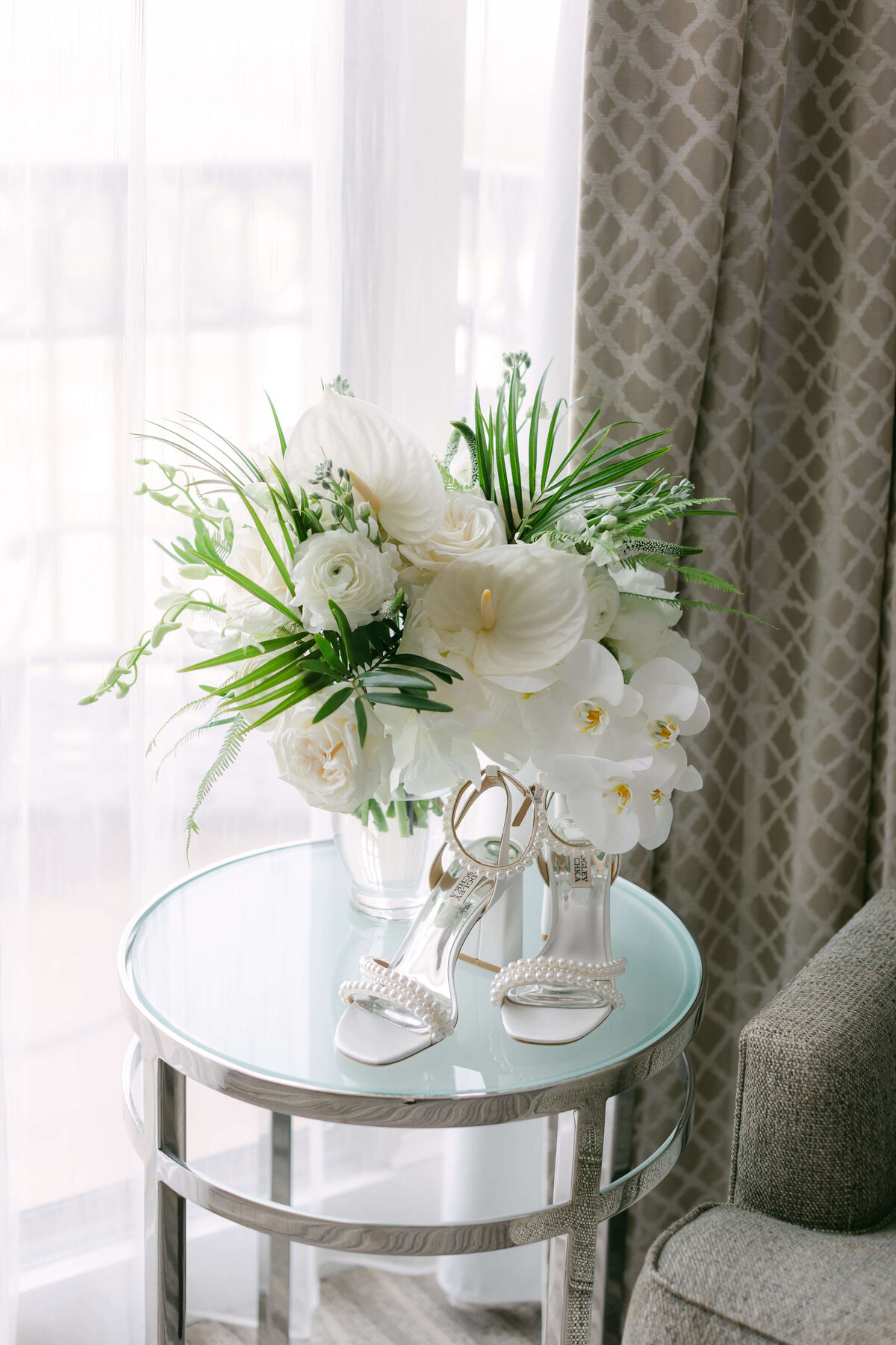 White flowers and palms sit on a bedside table.