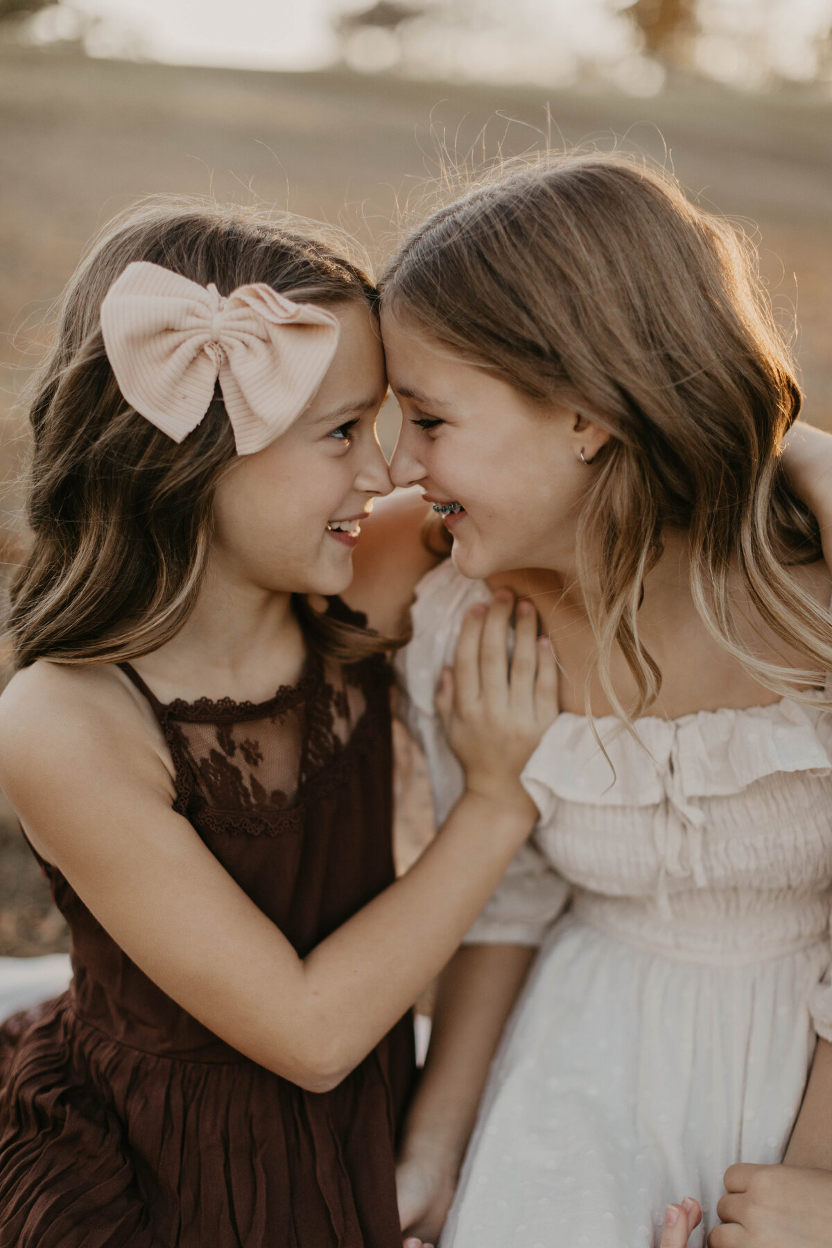 Two sisters touching noses during a fall session. 