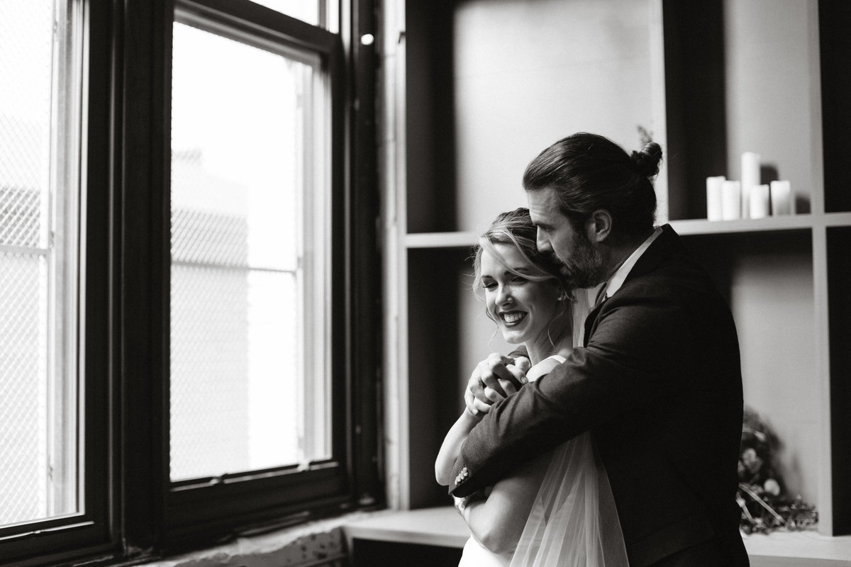 Bride and groom snuggle up for a photo after family portraits in this unique event space at Bok.