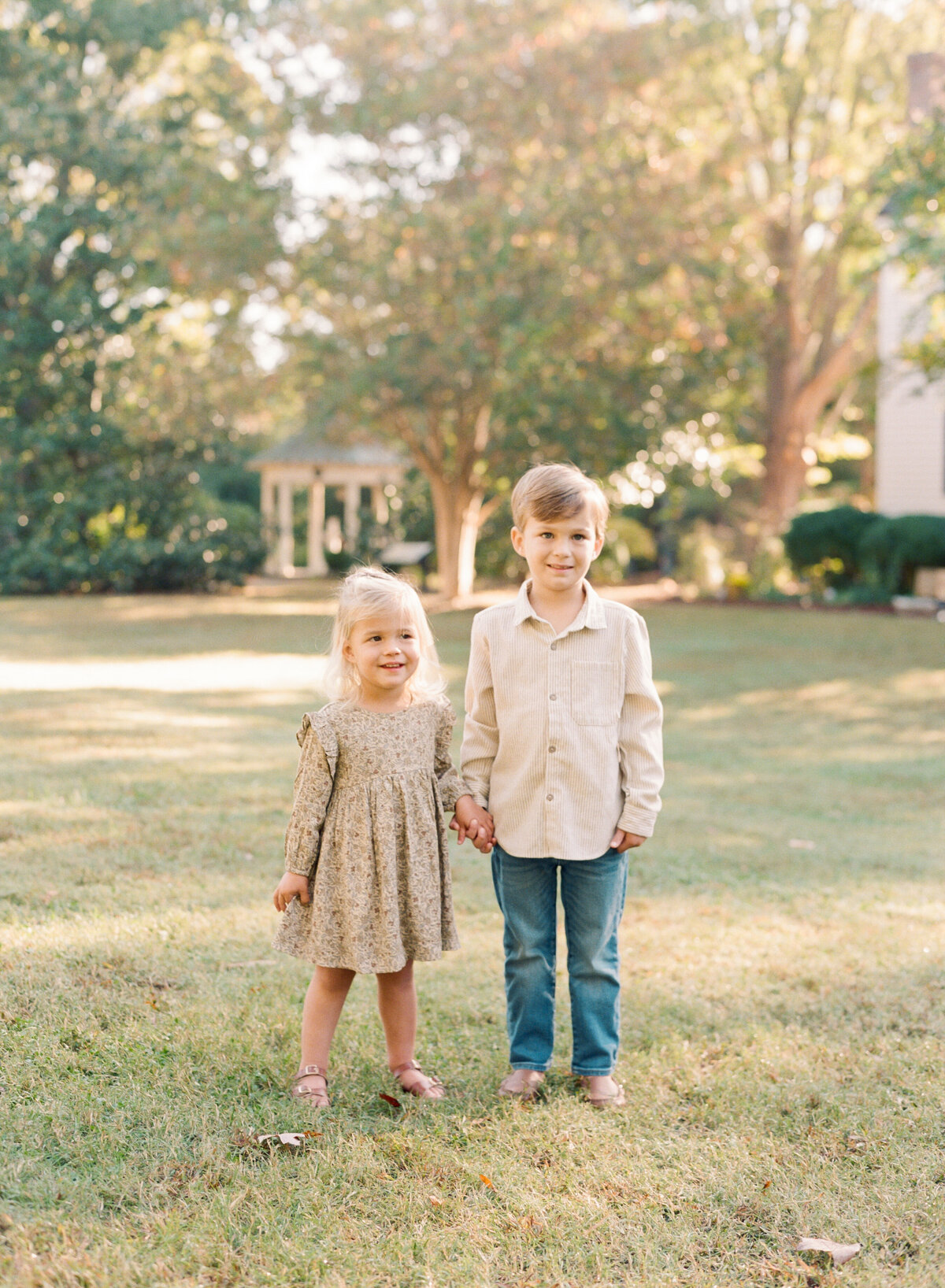 Siblings smile during their fall family photos in Raleigh NC. Family walking during their family portrait session in Wake Forest, NC. Photographed by Raleigh family photographer A.J. Dunlap Photography.