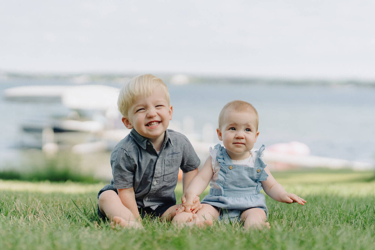 Toddler and a baby sitting on grass at generational photoshoot in Finger Lakes, NY