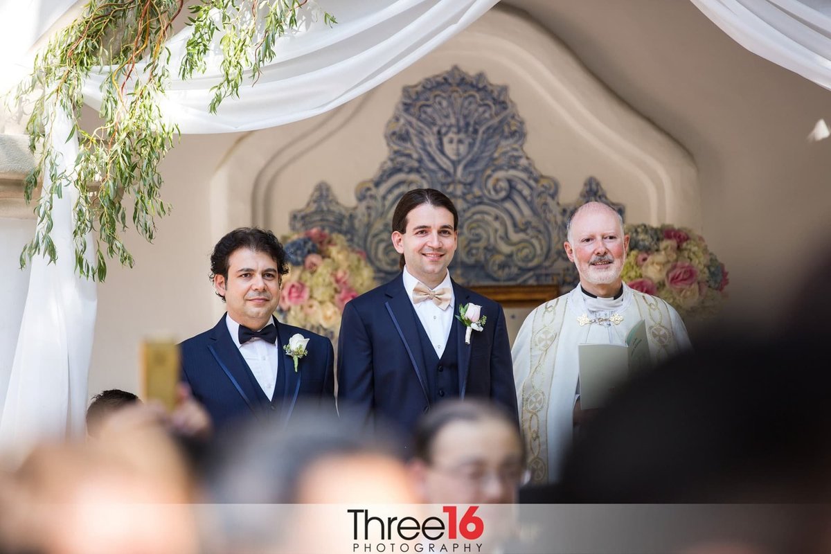Groom smiles as he watches his Bride walk up the aisle, while the best man and officiant watches