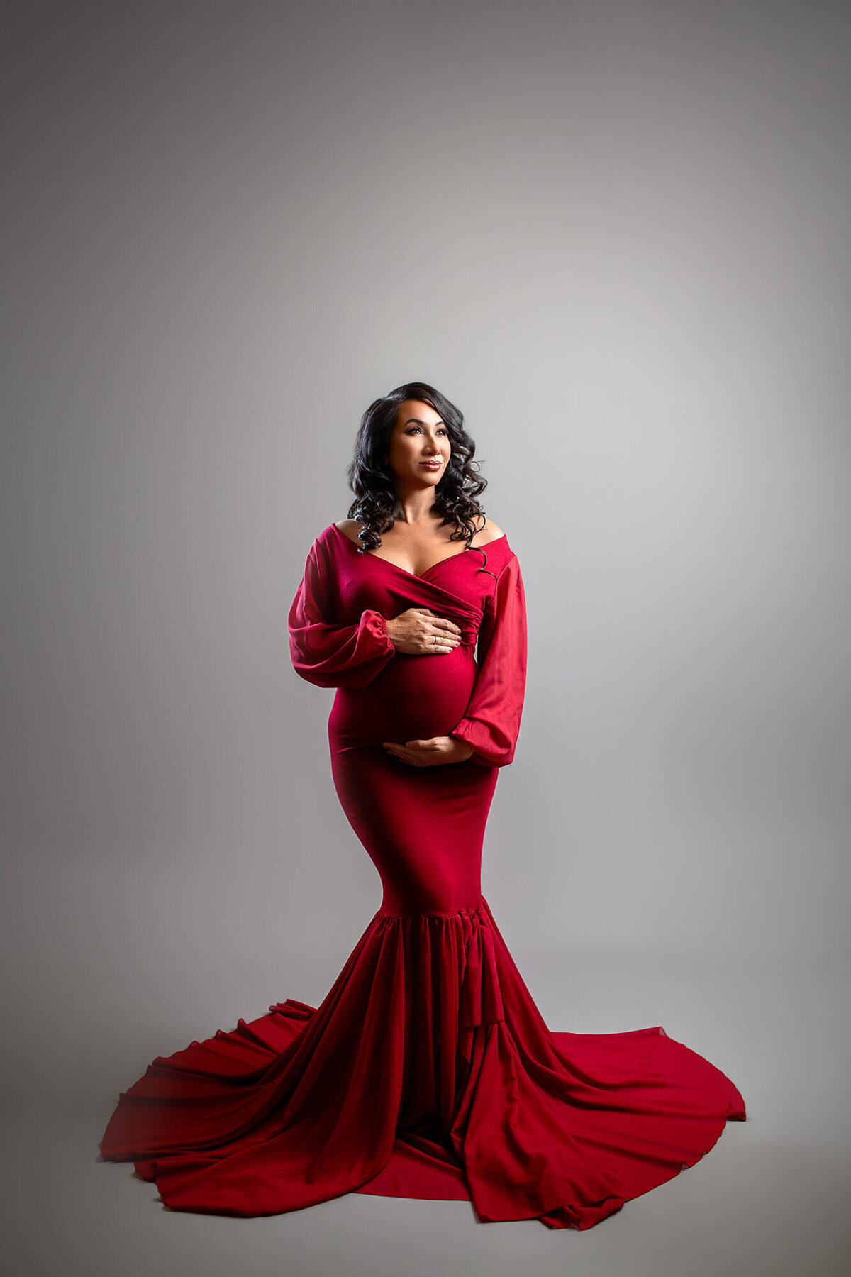 Studio maternity session with dark haired woman in mermaid style red dress 
