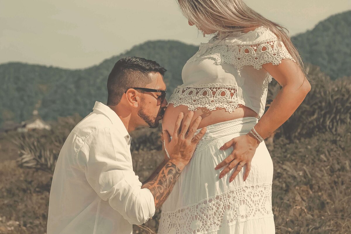 Man Wearing White Dress Shirt Kissing Woman on Her Baby Bump