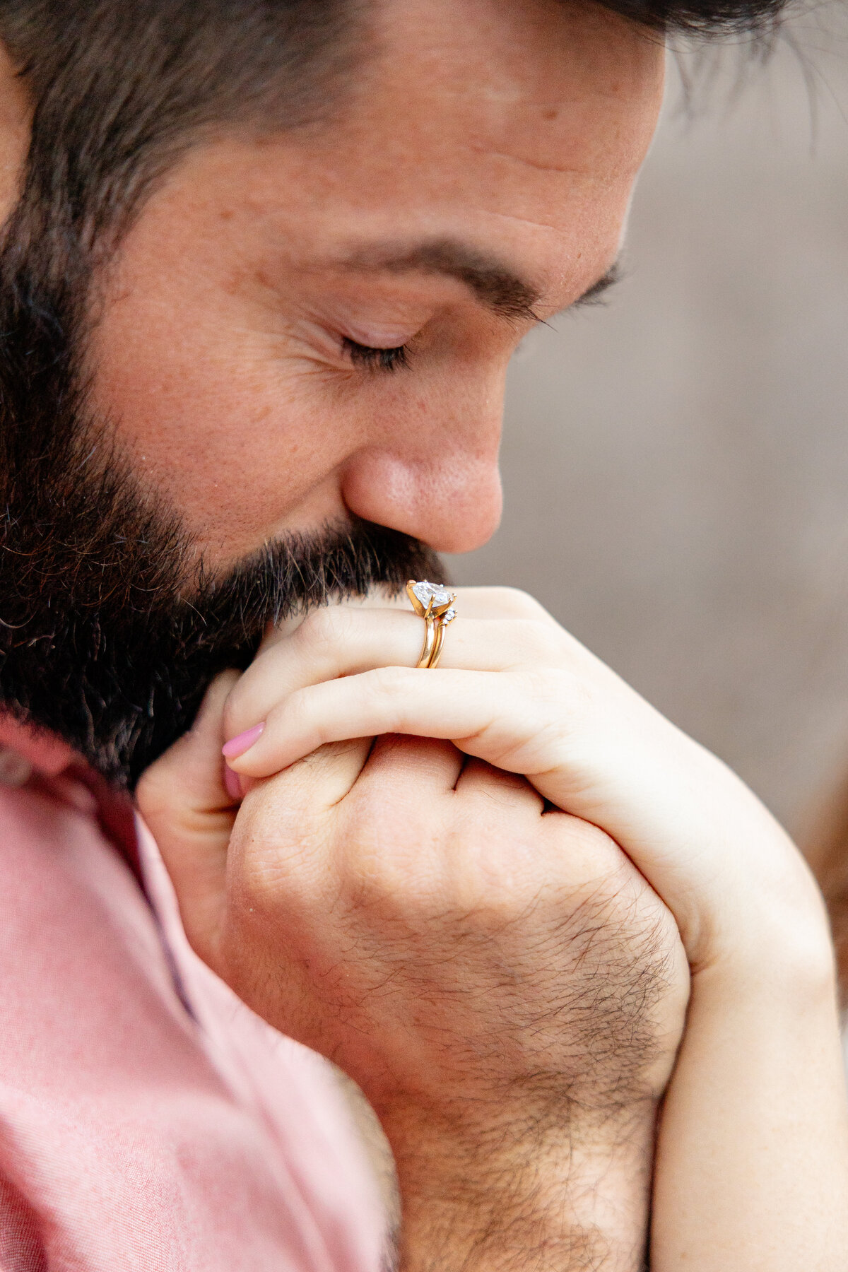 Groom-to-be kissing his fiancée’s hand, highlighting a gold engagement ring with a unique diamond setting during their Utah engagement shoot.