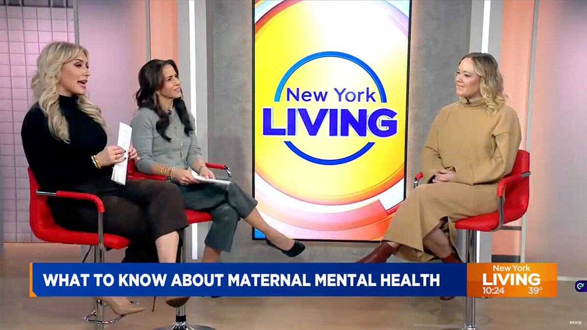 Three women sit on chairs chatting with a New York living news anchor in a bright studio setting.