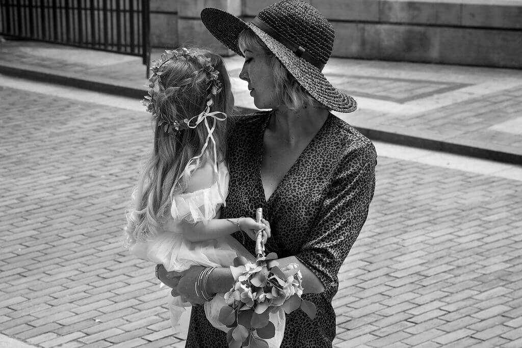 Brompton Oratory wedding guest holds her flower girl daughter