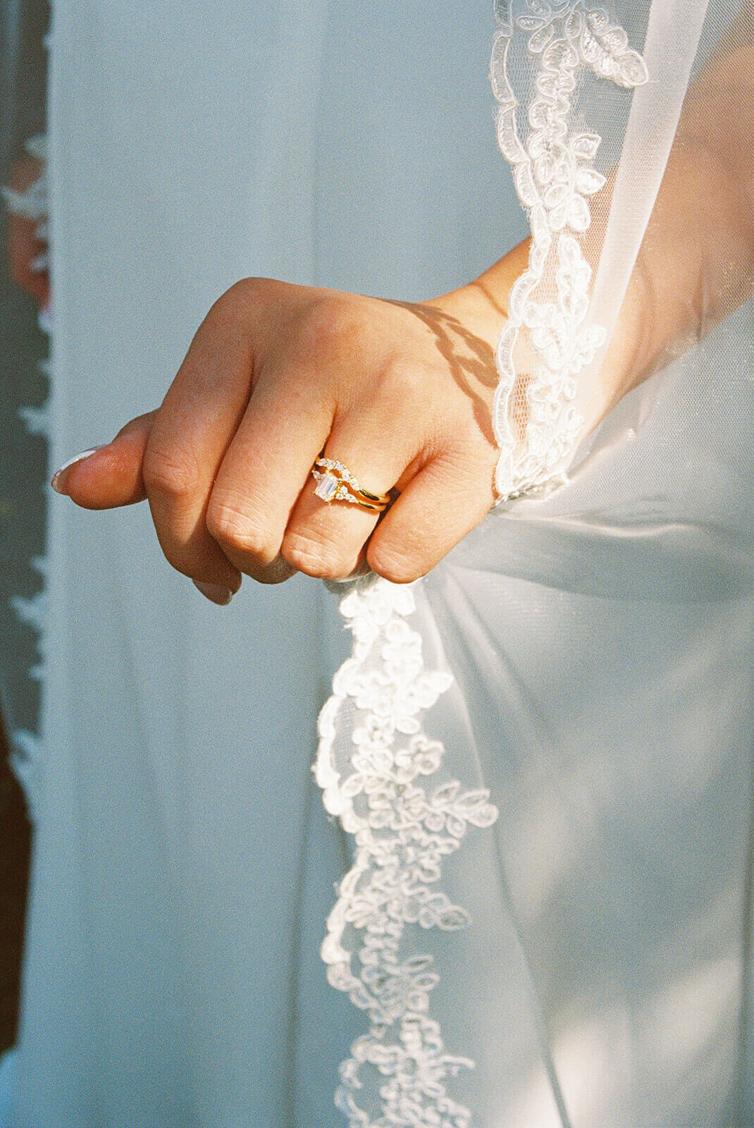 Close up women's hand wearing an engagement ring and holding her veil.
