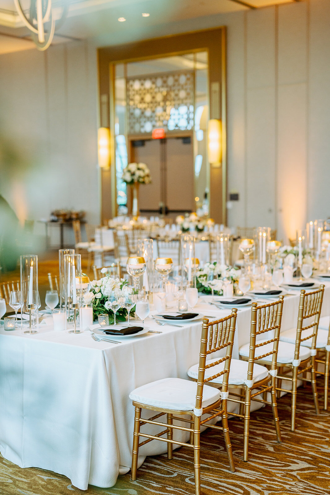White reception tables with gold chairs and candles on table
