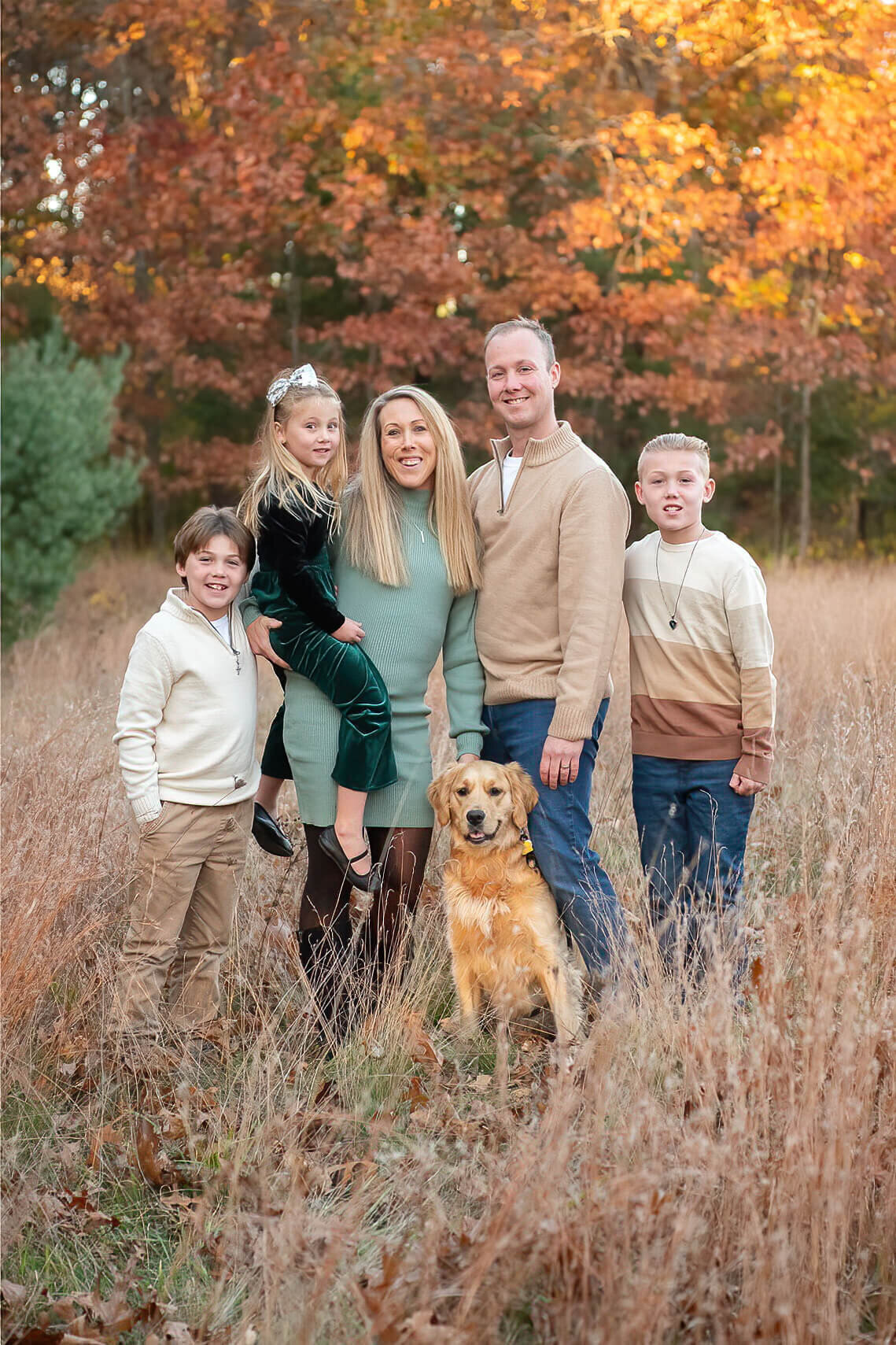 A family of five wade through the tall grass of Minute Man trail with their Golden Retriever.