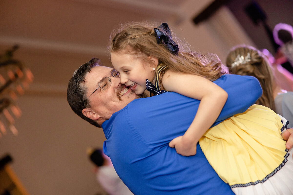 father dances with little girl in yellow dress at wedding