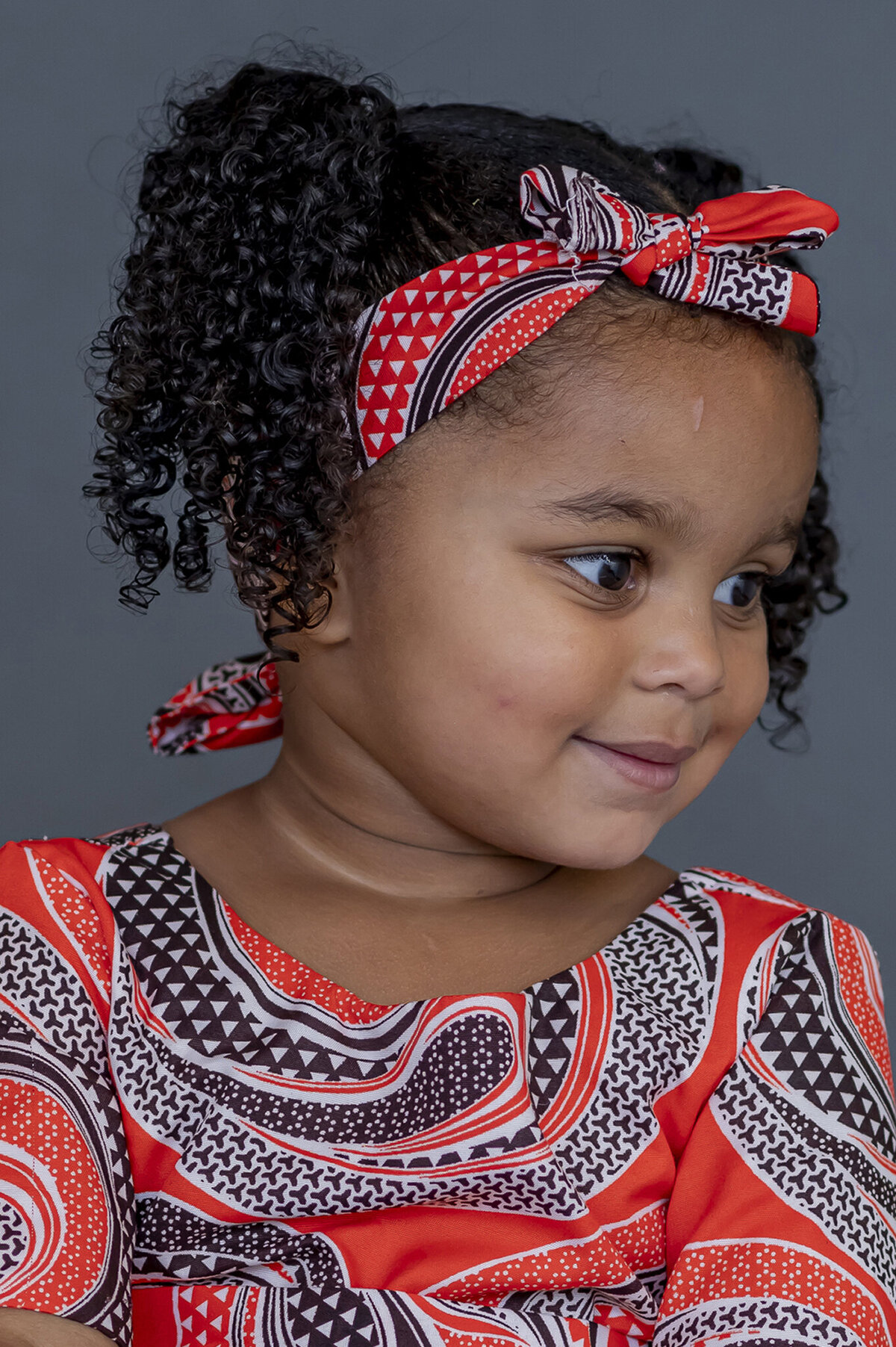 Preschool girl looking to her left showing her profile and smiling