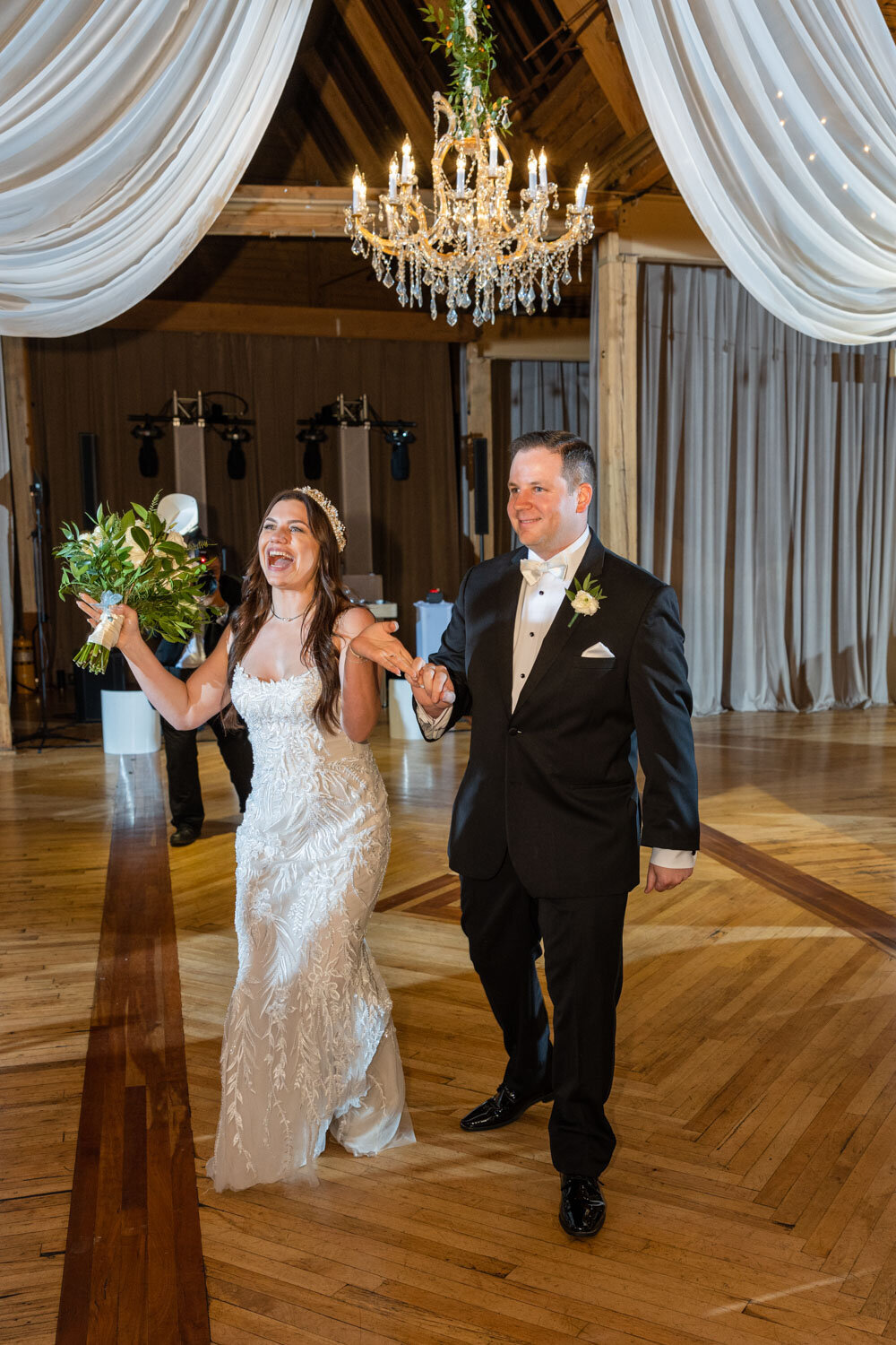 A bride and groom are walking down a wooden floor