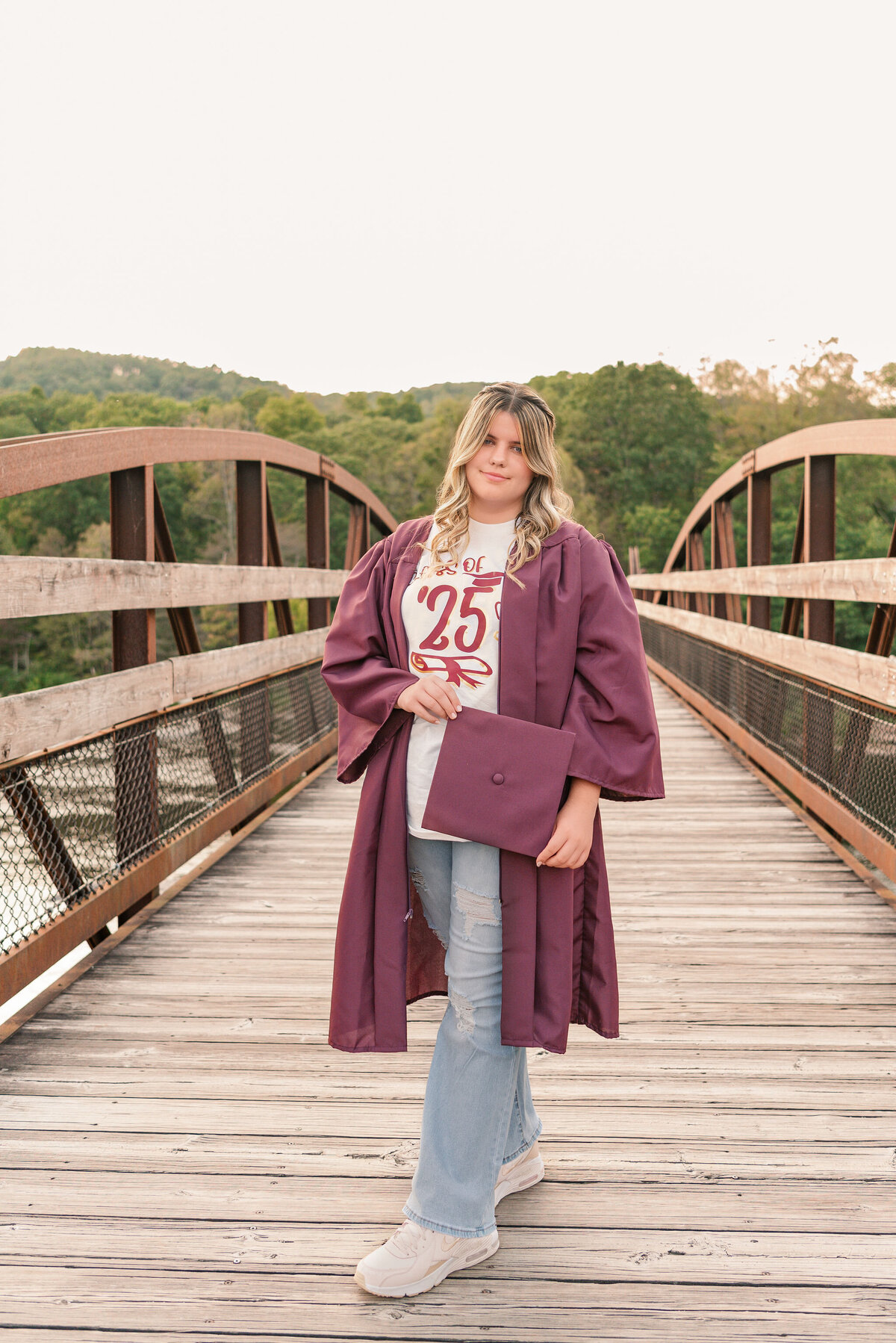 Full-length senior portrait on Ohiopyle’s wooden bridge in cap and gown — Class of 2025 photos by Lens Love Photography