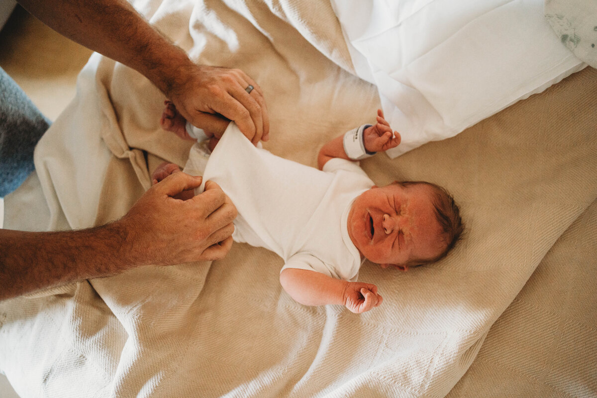 Baby boy wrapped in a blue swaddle with matching bonnet in a bamboo basket in a Rio, WI newborn studio.