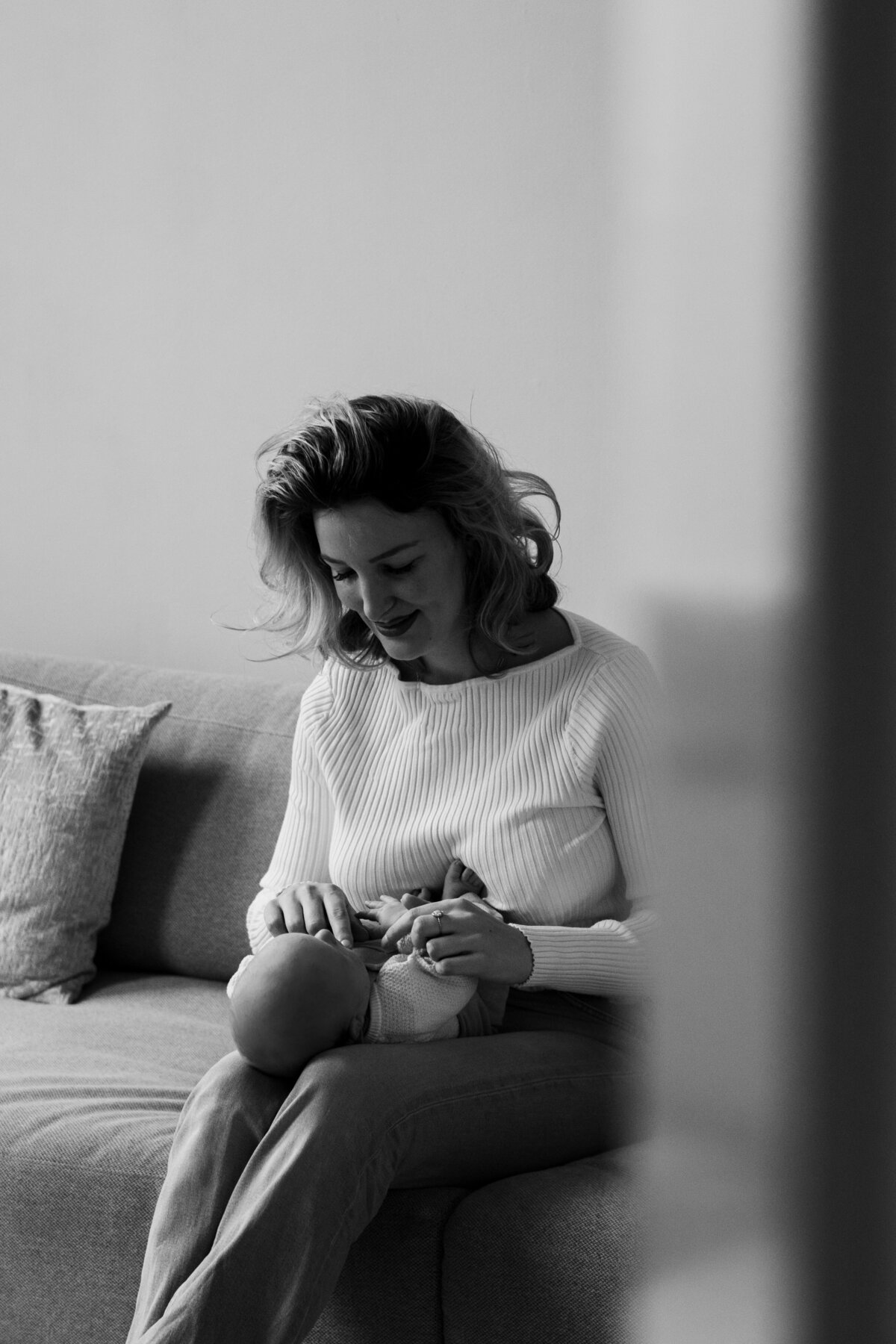 Een vrouw zit op een bank en houdt haar baby liefdevol vast.