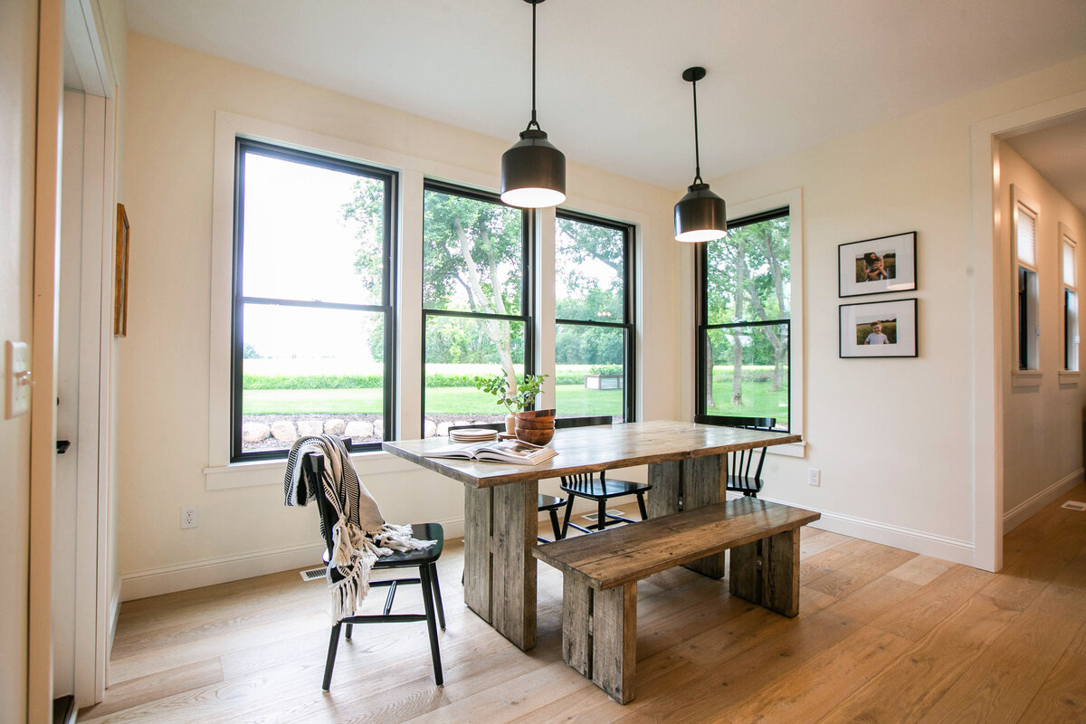 Open kitchen with eat in dining area, white cabinets, large island, and quartz countertops in an Otsego custom home